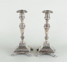 A pair of silver candlesticks on a square base, standing on claw feet, with multi-sided stem