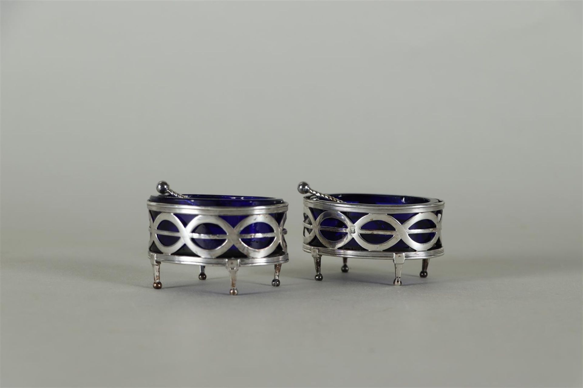 A set of (2) silver Louis XVI salt cellars with blue glass and matching spoons. 