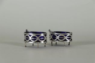 A set of (2) silver Louis XVI salt cellars with blue glass and matching spoons.