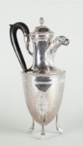 A silver jug on three high legs, with an acorn-shaped knob on the lid and with rich leaf decoration 