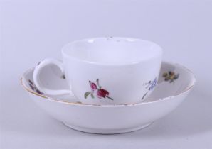 A cup and saucer with floral decor, marked on the bottom.