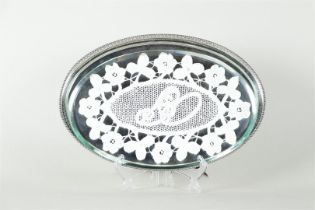 A silver tray for two glasses or cream set. On top of that a cut glass plate and bobbin lace doily.