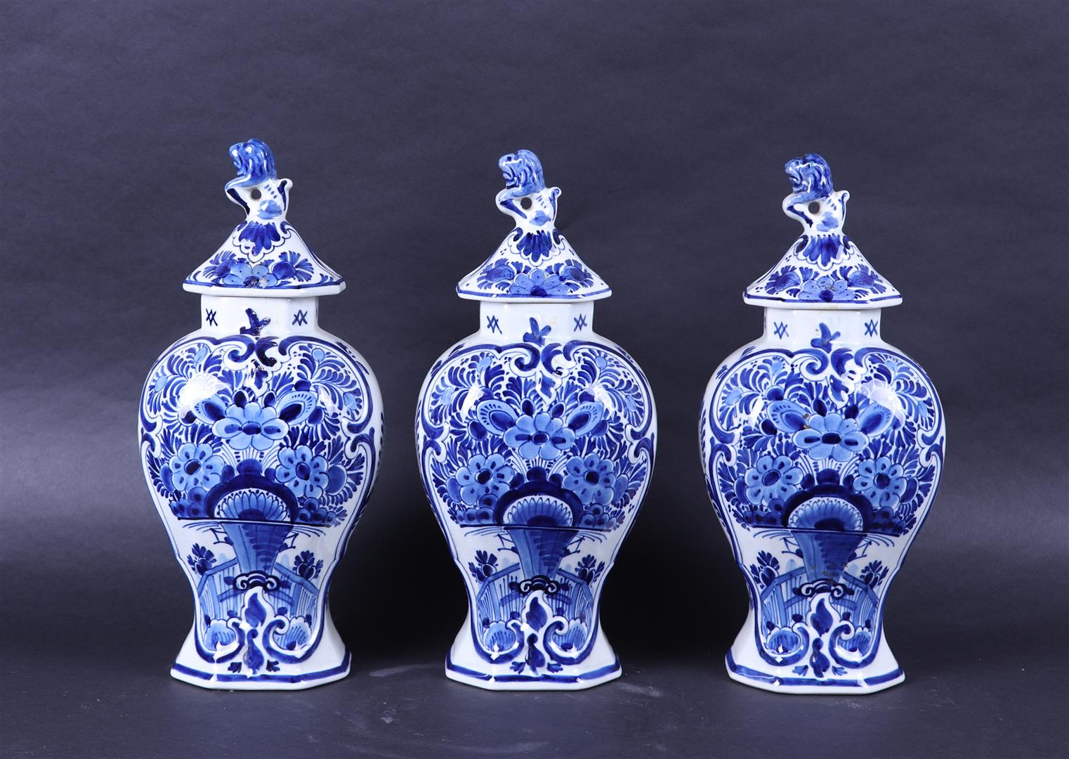 A set of three earthenware cupboard vases with flower basket decor. Porceleyne bottle.
