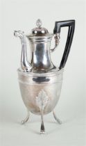 A silver jug on three high legs, with an acorn-shaped knob on the lid and with rich leaf decoration 