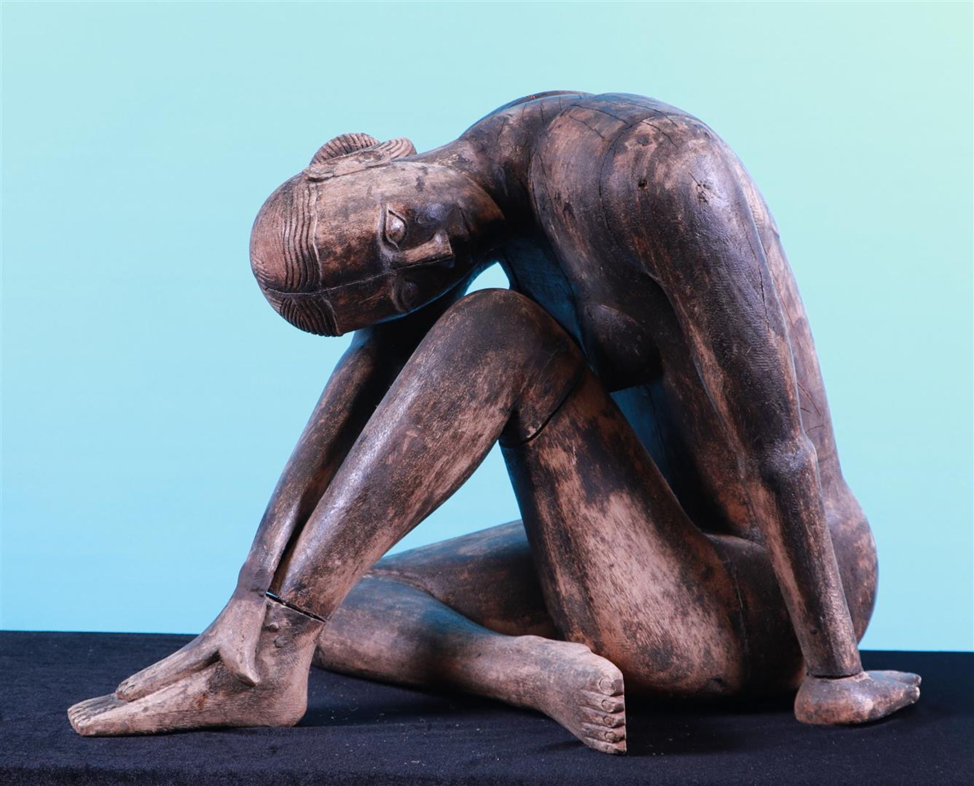 A large wooden sculpture of a seated lady.
