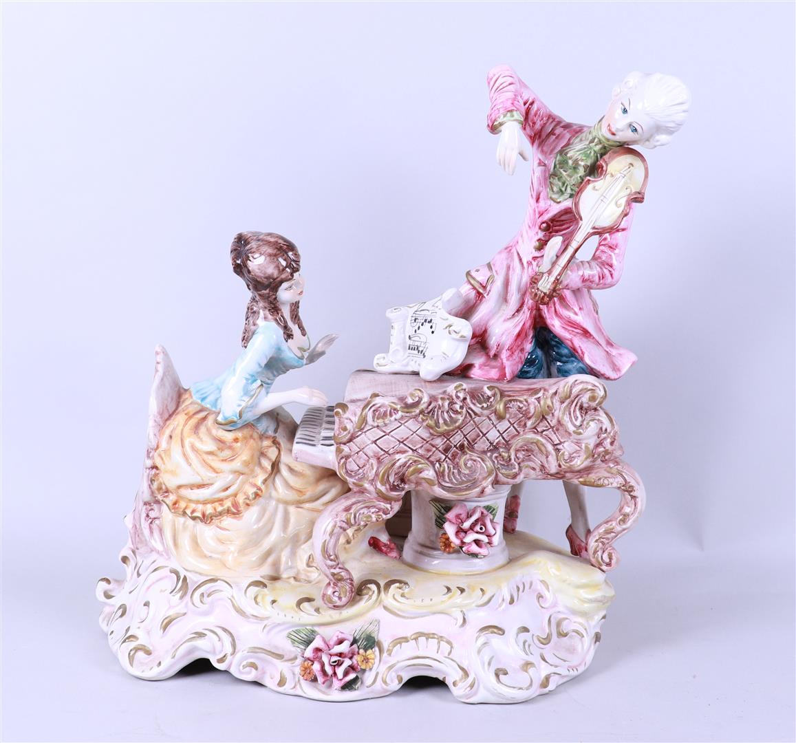 An earthenware statue of a couple playing music, marked Capodimonte.