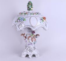 A porcelain table lamp decorated with puti on the base and plaques with plaques on the shade, marked