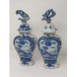 A pair of 19th Century Dutch delft lidded Vases with bird finials and panels of boy fishing A/F 12in