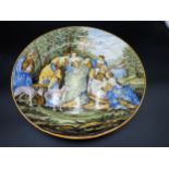 A maiolica Charger, painted figures with baby and dogs besides a bridge in wooded landscape, 14½