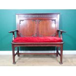 A Chippendale style mahogany settle with blind fret carved frieze, shaped arms and red cushioned