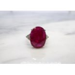 A Ruby and Diamond Ring claw-set oval-cut ruby, 11.43cts, between trios of brilliant-cut diamonds in