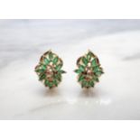 A pair of Diamond and Emerald Cluster Earrings each claw-set three brilliant-cut diamonds within