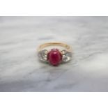 A Ruby and Diamond three stone Ring claw-set oval ruby cabochon between two brilliant-cut