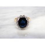 A Sapphire and Diamond Cluster Ring claw-set oval-cut sapphire, 3.28cts, within a frame of