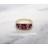 A Ruby and Diamond Ring pavé-set three graduated oval-cut rubies interspersed with pairs of old-