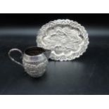 An Indian silver Jug and small oval Tray embossed and chased hunting scenes, landscape frieze, etc