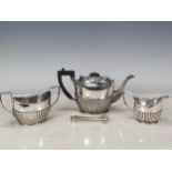 An Edwardian silver three piece Tea Service of semi-lobed design and ebonised handle and finial to
