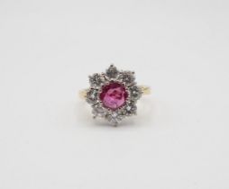 A Ruby and Diamond flower Cluster Ring claw-set round ruby within a frame of eight brilliant-cut