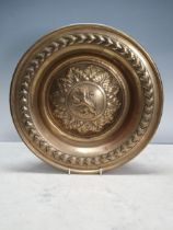 An embossed brass Dish with central rampant lion, 12in diam