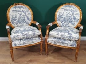 A pair of French gilded open Armchairs, moulded top rails in the form of musical instruments with