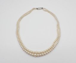 A double row of graduated Cultured Pearls on 18ct white gold clasp pavé-set three brilliant-cut