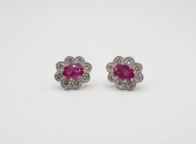 A pair of Ruby and Diamond Cluster Earrings each claw-set oval-cut ruby within frame of eight