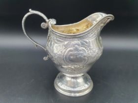 A George III silver Jug with floral swag embossing, leafage scroll handle on pedestal base, London