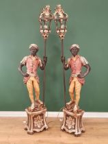 A pair of blackamoor Figures holding lanterns with painted finish and standing on plinth, 6ft 8in