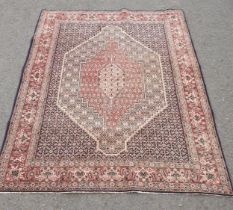 A modern Persian Rug with pink central lozenge on blue ground with pink border with stylised flowers