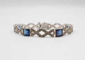 An Art Deco style Bracelet millegrain-set square blue paste interspersed with XX links set white