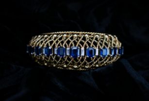 A Gubelin Sapphire and Diamond Bangle of graduated bombé form corner claw-set a row of graduated