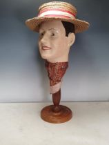 A papier mache Bust of a man wearing a boater and scarf on a turned wood stand, 23in H