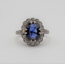 A Sapphire and Diamond Cluster Ring claw-set oval-cut sapphire within a frame of millegrain-set