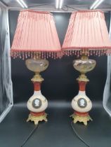 A pair of converted Oil Lamps with floral painted reservoirs, brass mounted baluster bases with