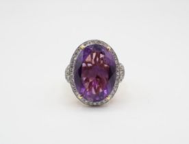 An Amethyst and Diamond Cluster Ring claw-set oval-cut amethyst within a frame of pavé-set