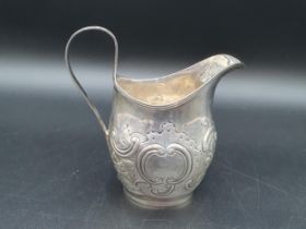 A George III silver oval Jug with floral and scroll embossing, engraved crest, London 1803