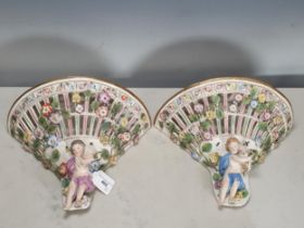 A pair of Meissen style floral encrusted Wall Brackets of pierced design and mounted cherubs, 8 1/