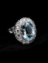 An Aquamarine and Diamond Cluster Ring claw-set oval mixed-cut aquamarine within a frame of pavé-set