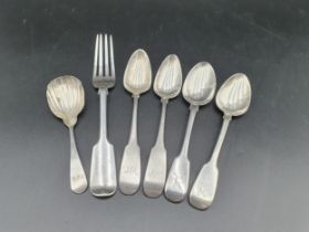 An Irish silver Caddy Spoon with scallop bowl engraved initials, a silver Fork and three Teaspoons