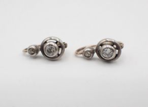 A pair of Diamond Earrings each rubover-set old-cut stone below smaller stone in silver backed