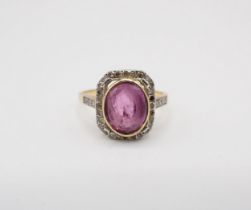 A Pink Sapphire and Diamond Cluster Ring rubover-set oval-cut sapphire within a frame of eight-cut