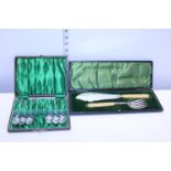A boxed fish serving set with silver mounts and one other set of vintage cutlery