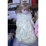 A porcelain headed doll on stand