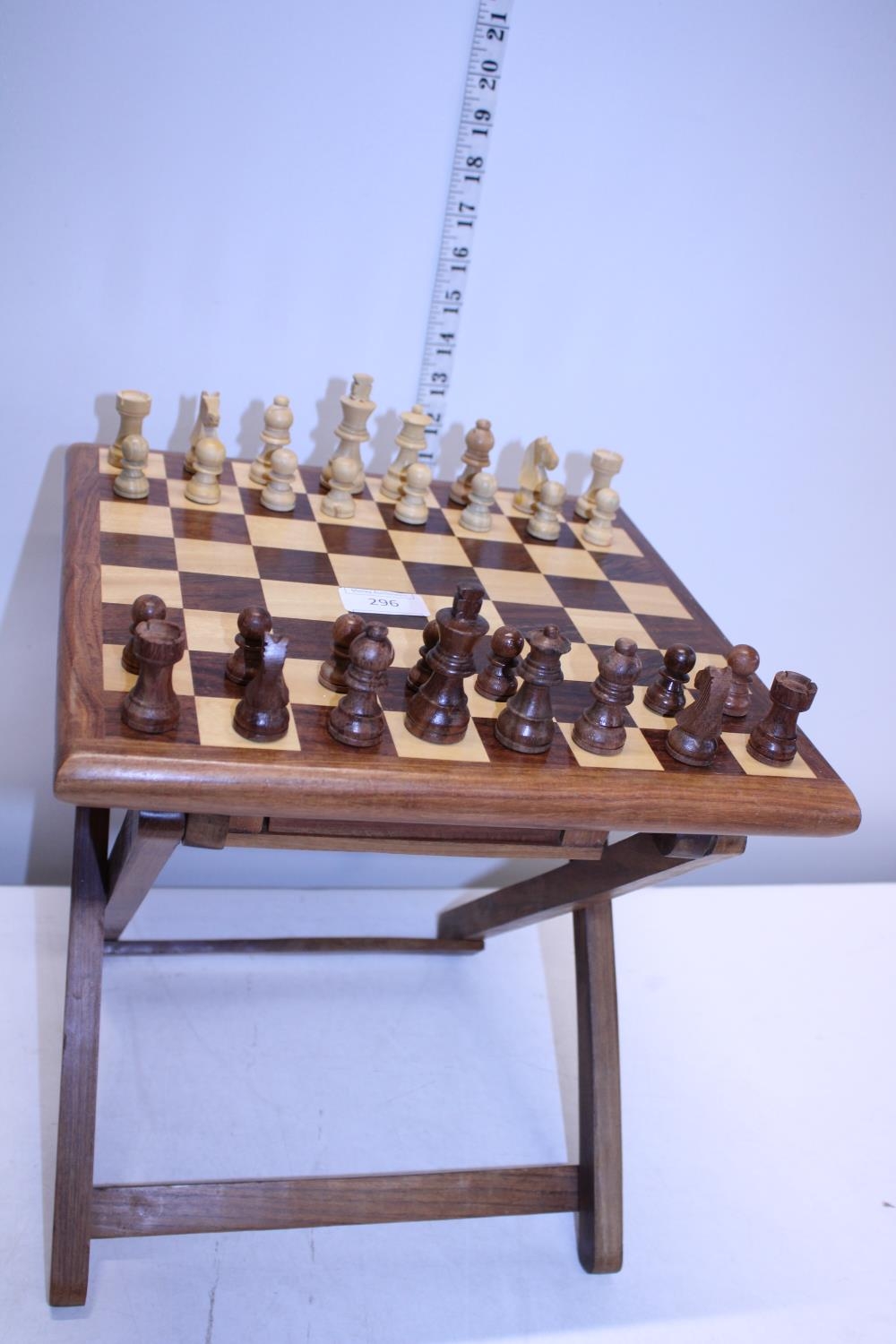 A portable wooden chess board with wooden pieces (missing one pawn)