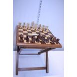 A portable wooden chess board with wooden pieces (missing one pawn)