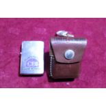 A brass Zippo lighter with leather pouch