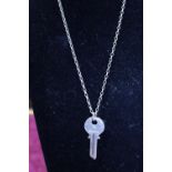 A hallmarked silver key on silver chain