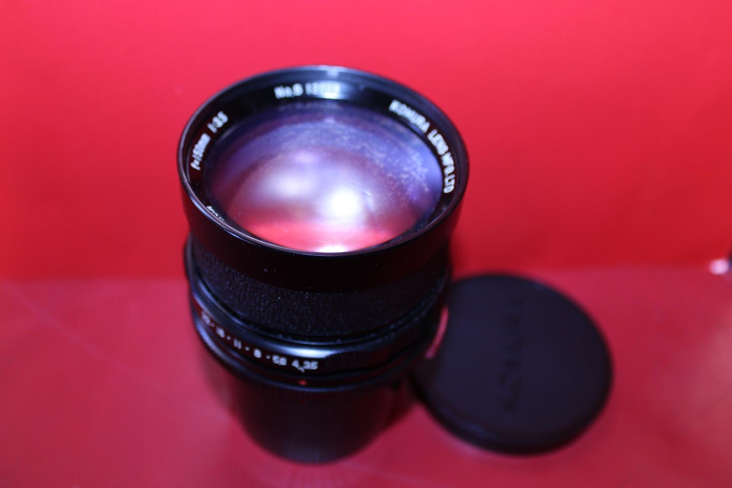 A cased Komura camera lens F=150m