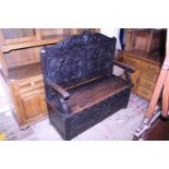 A late 19th century monks bench with storage under seat, hand carved back with Green Man motif