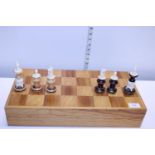 A maple wood chess board with a selection of wooden and bone chess pieces